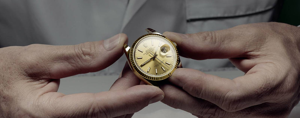 A close-up of a used Rolex watch being inspected by a professional.